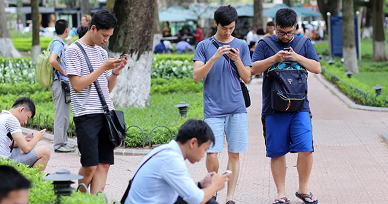 Nhóm nam thanh niên đang sử dụng điện thoại thông minh tại công viên