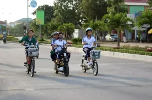 Học sinh mặc đồng phục đi xe đạp điện an toàn trên đường phố Việt Nam
