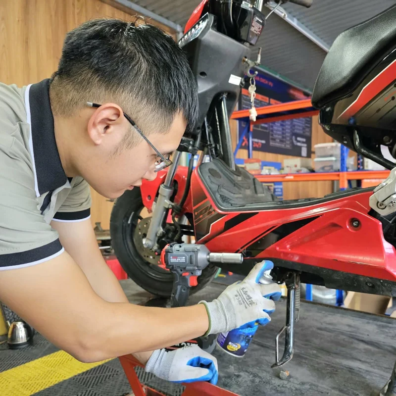 Thợ kỹ thuật đang bảo dưỡng xe máy điện trong xưởng sửa chữa chuyên nghiệp